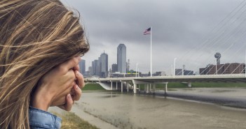 Easter Vigil Brings the Story of Salvation to a City in Need Stock photo of a woman with her face buried in her hand standing by a city waterfront