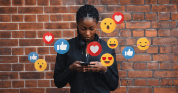 Person looking at social media on their phone while icons appear in the air around them